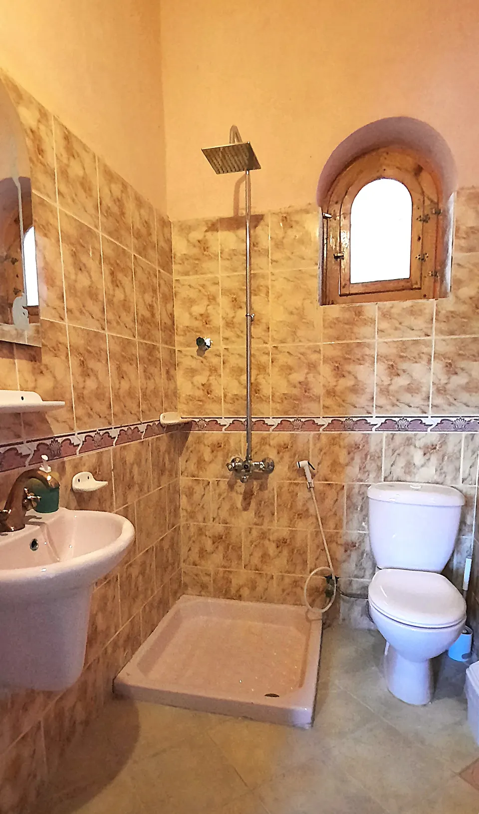 A bathroom with a stone wall and arched window · Standard