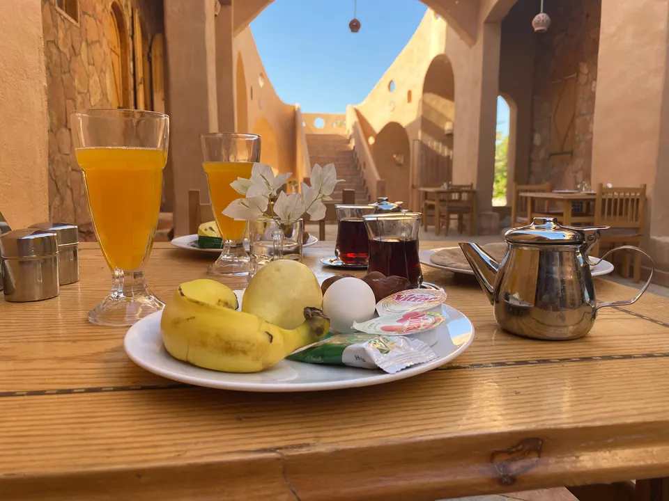 Breakfast with fruit, juice, tea and bread on a table in the lodge courtyard