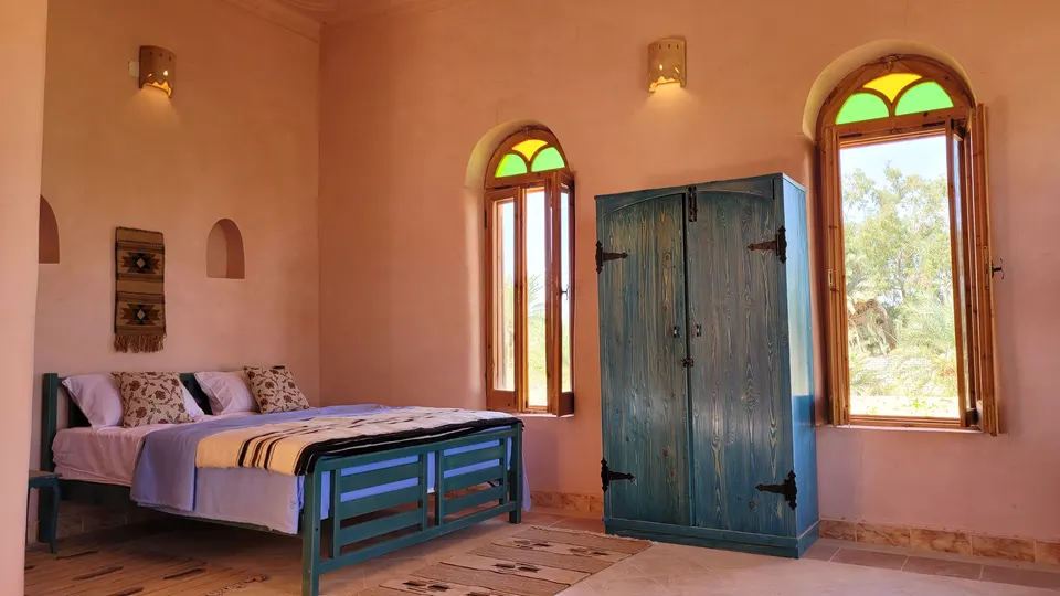 A room with coloured arched windows and a wooden door · Suite