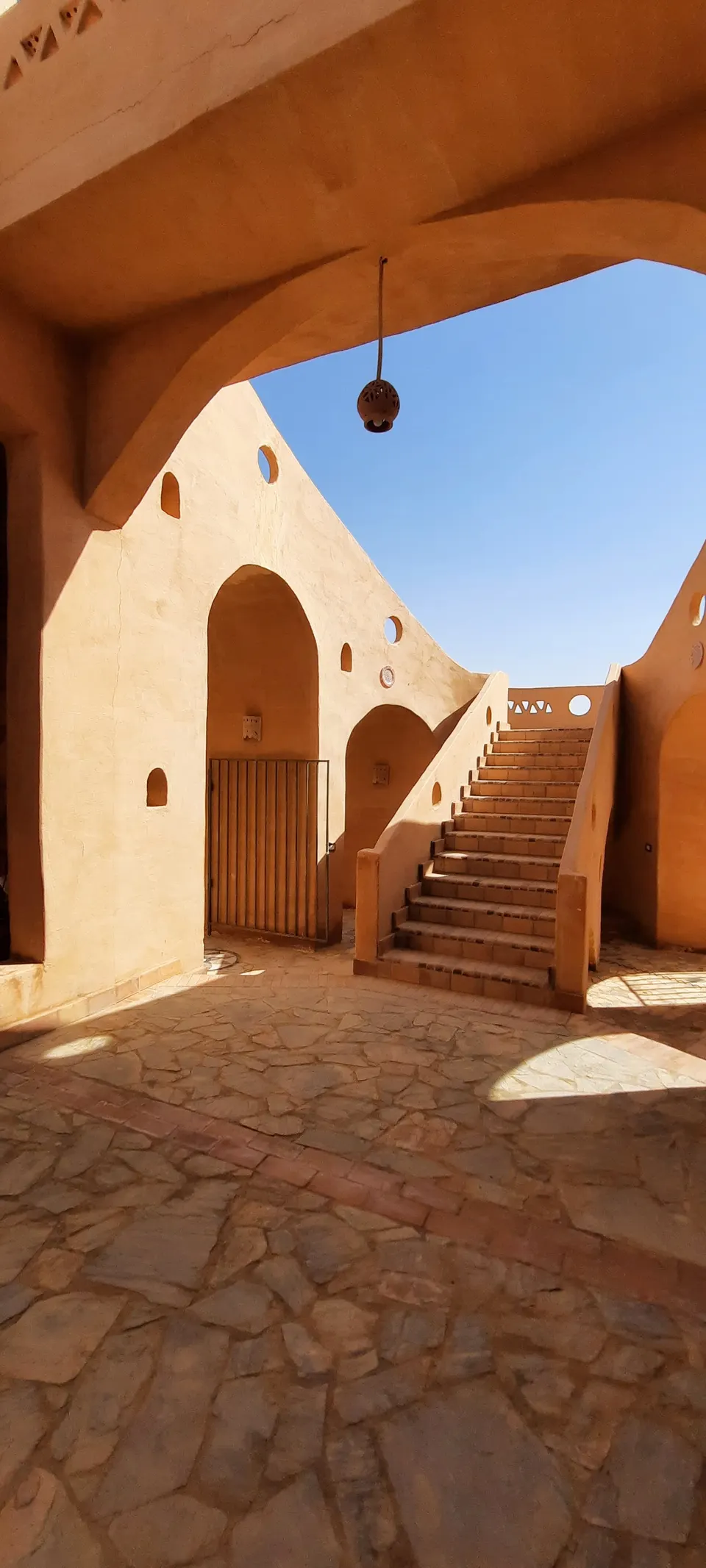 A sunlit courtyard and stairway framed by an arch
