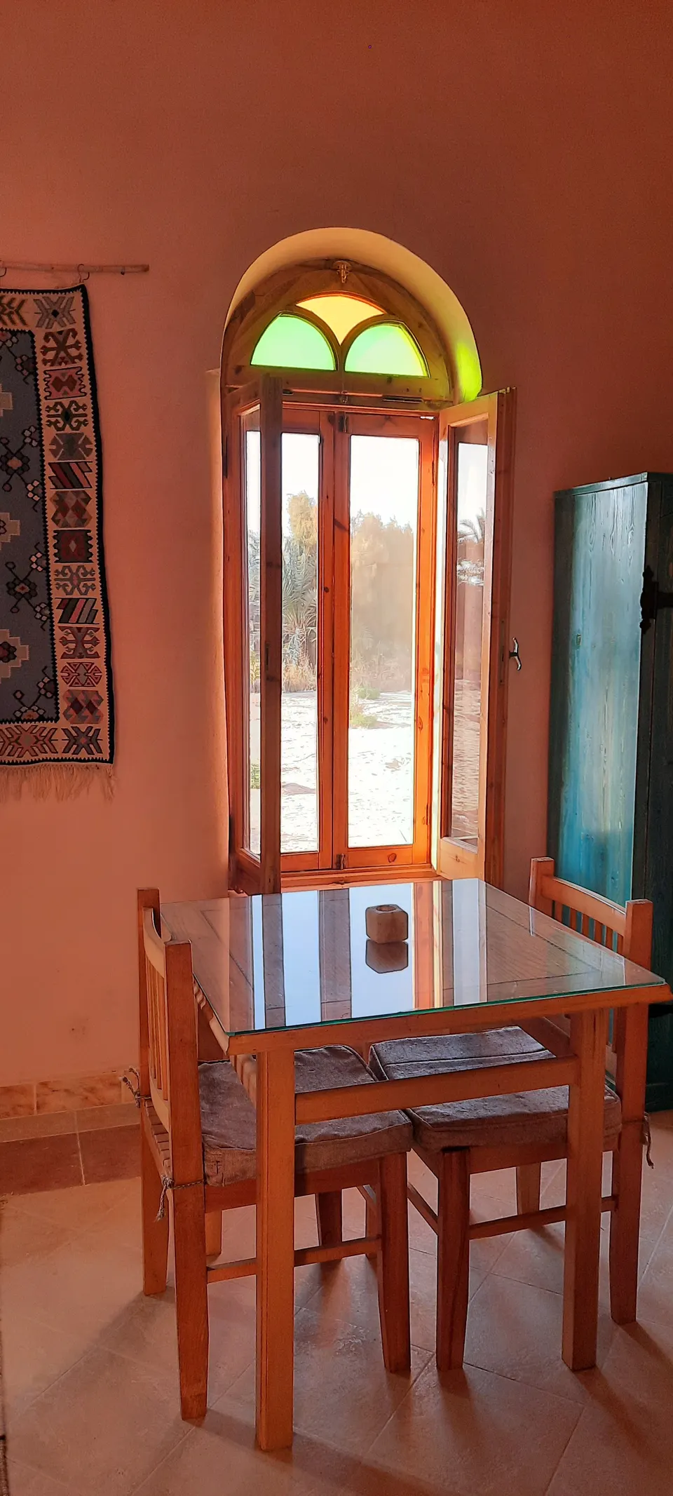 A wooden table beside a coloured arched window in the Suite