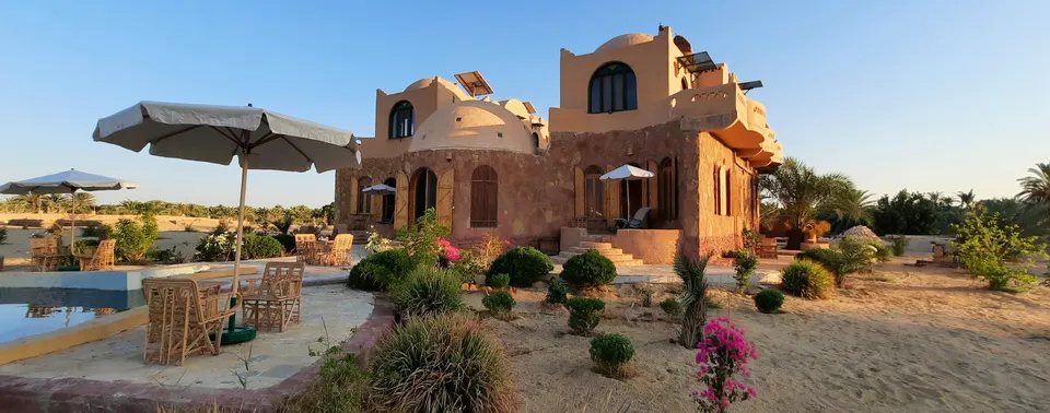 Siwa Salt Lake Lodge with sand-coloured domes, a garden and palm trees