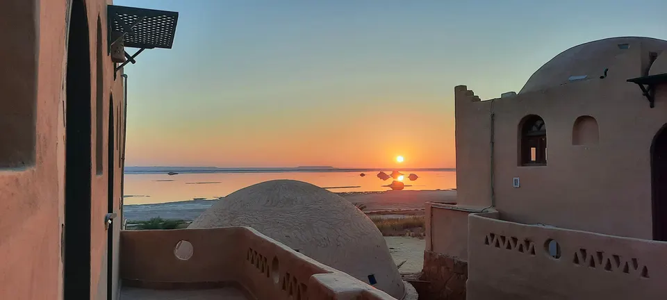 The low sun above the lake, framed by the lodge domes