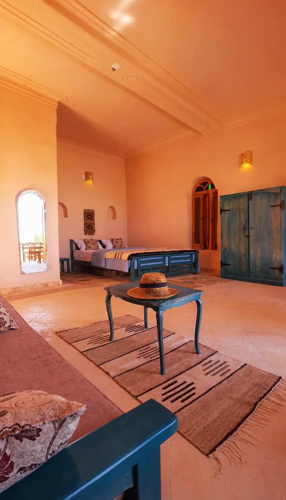 The Suite’s warm interior with a bed, seating area, blue wooden furniture and arched doorway